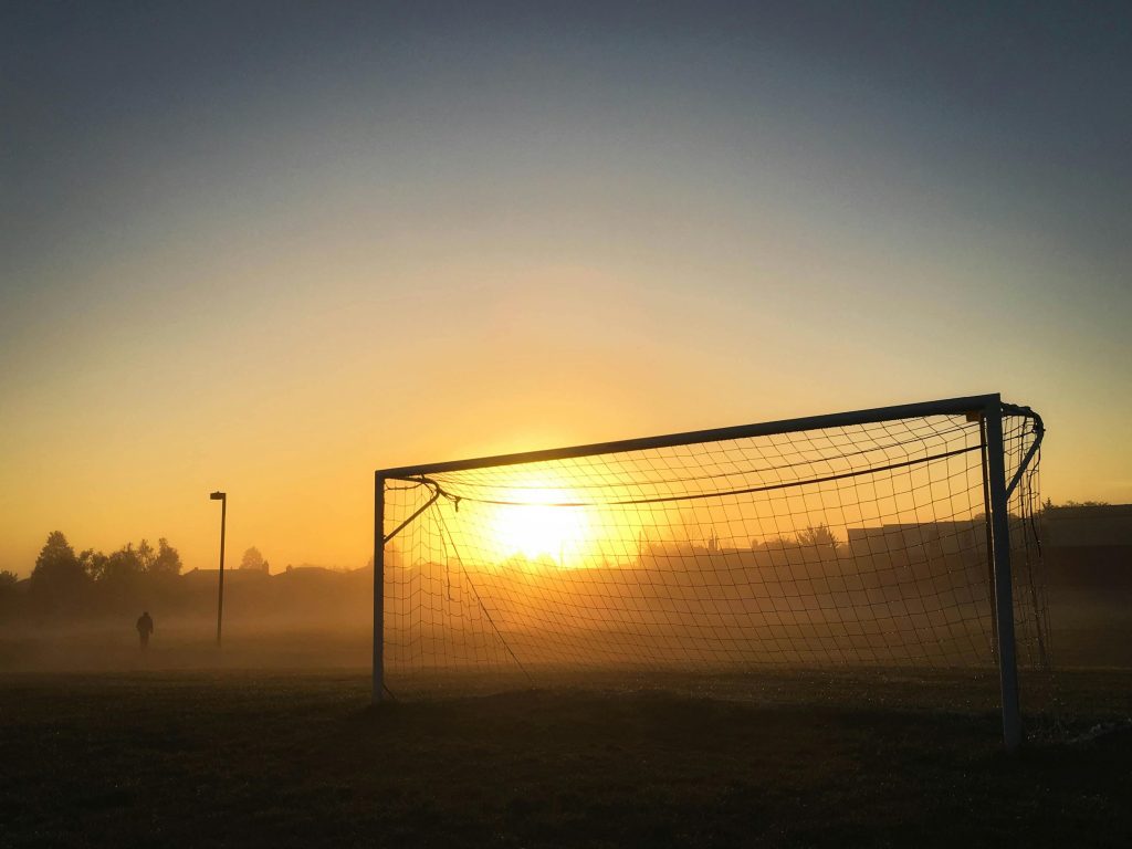 Soccer goal silhouetted against a misty sunrise in a tranquil Mississauga field.