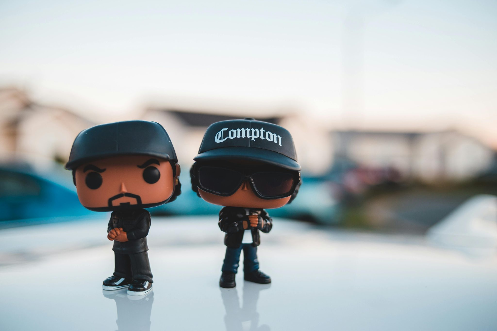 Small miniatures of cool men in stylish outfits and caps placed above shiny surface