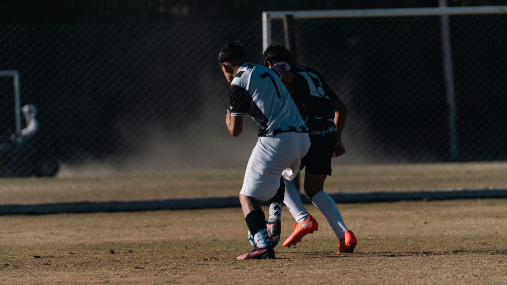 Two soccer players competing on a field during a daytime match.